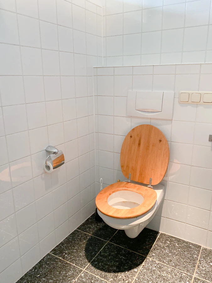 a bathroom renovation with a wooden toilet and white ceramic tiles on the walls