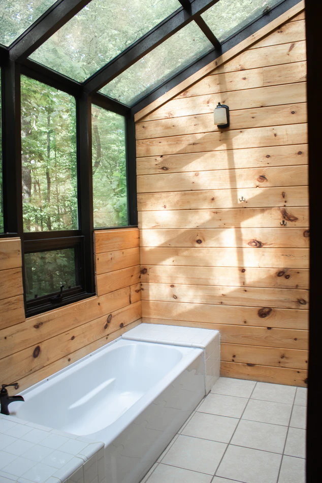 a small white bath in a pine wood cabin with glass windows
