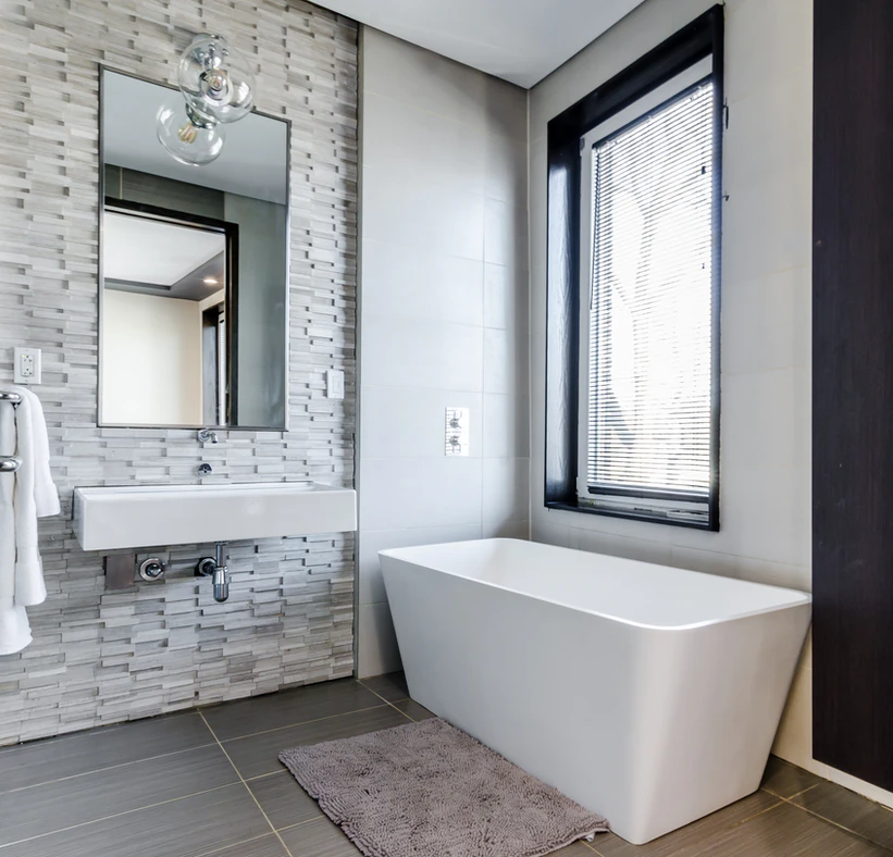 grey bathroom with textured wall pattern and a large white bathtub