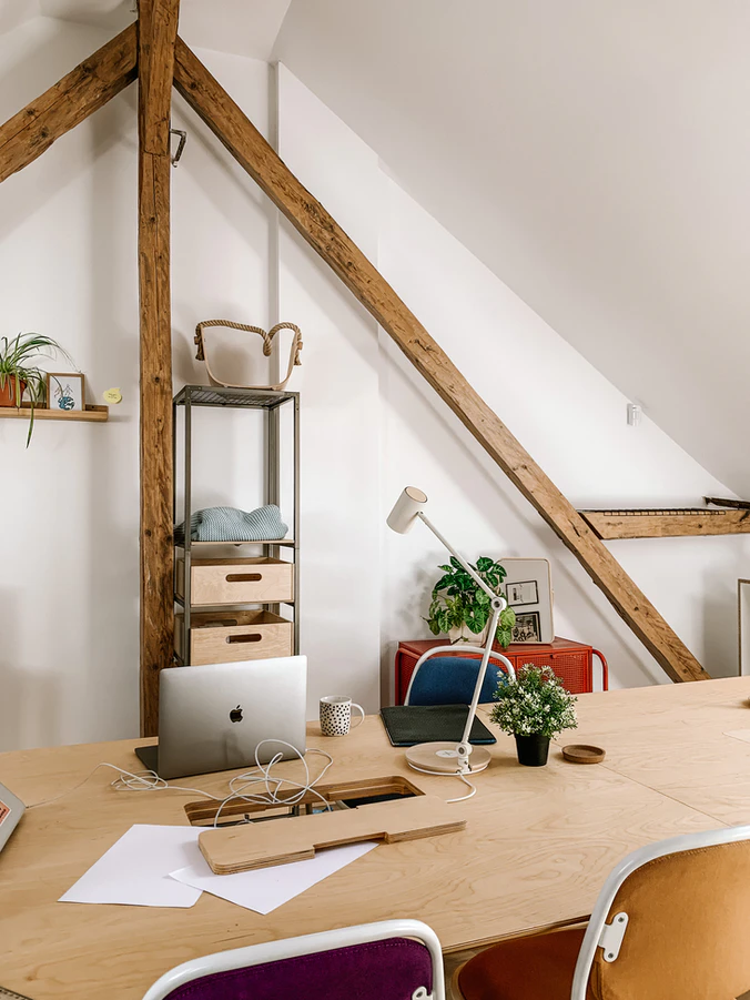 a wooden table with a mac m1 laptop and a lamp in a cozy loft