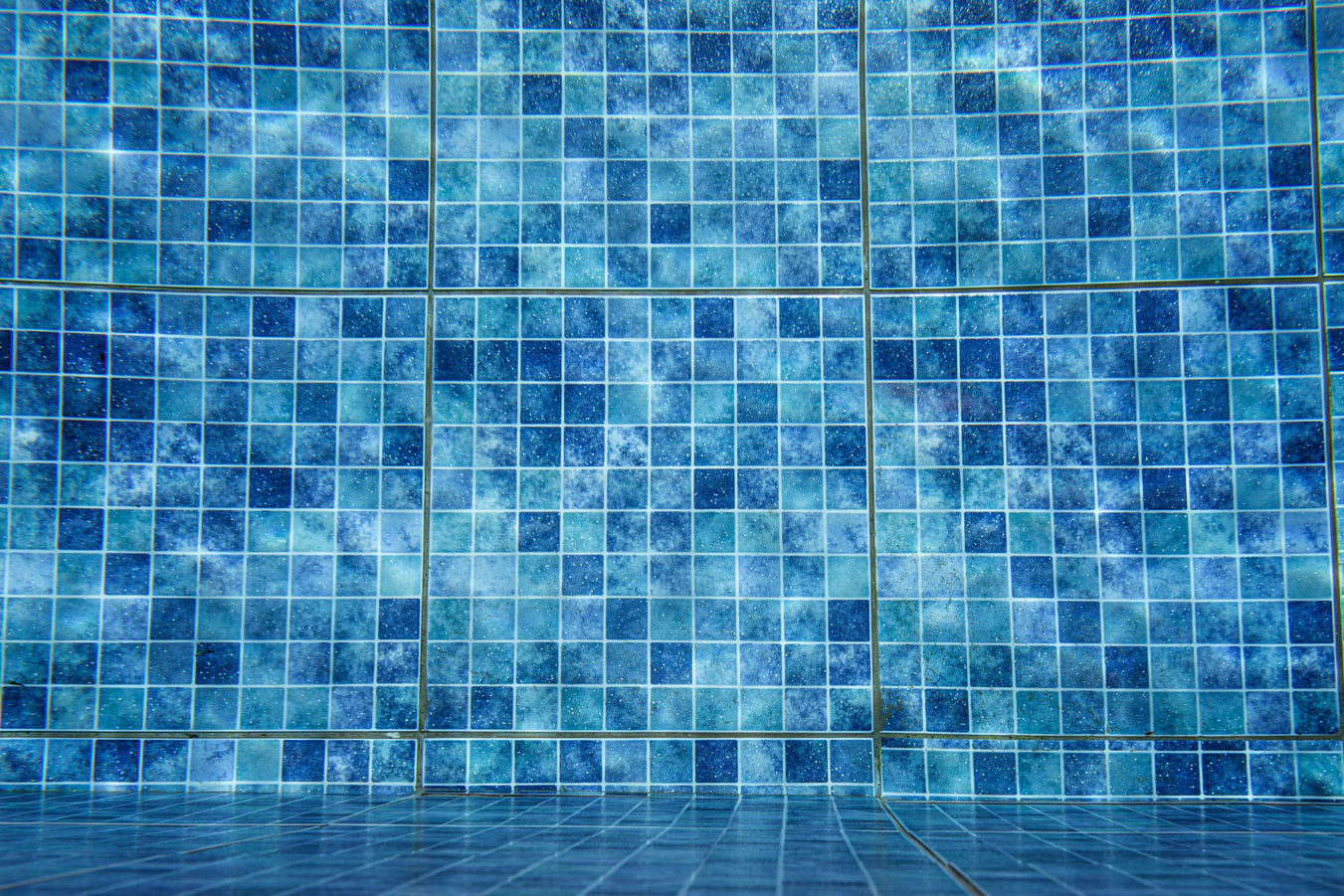small squares of mosaic blue tiles underwater in a pool renovation project